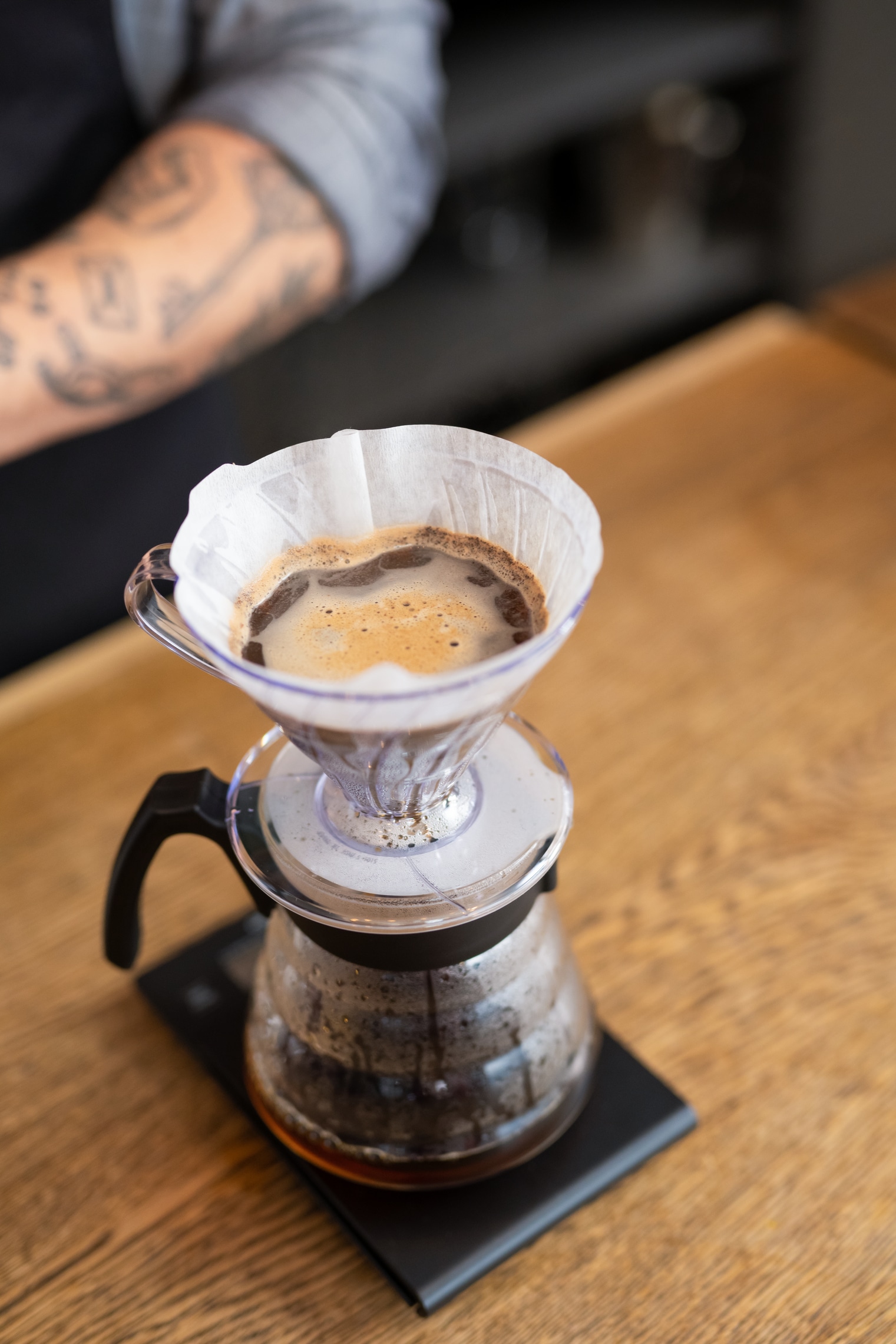 Pour-over coffee brewing in progress with a coffee dripper and filter on a glass carafe