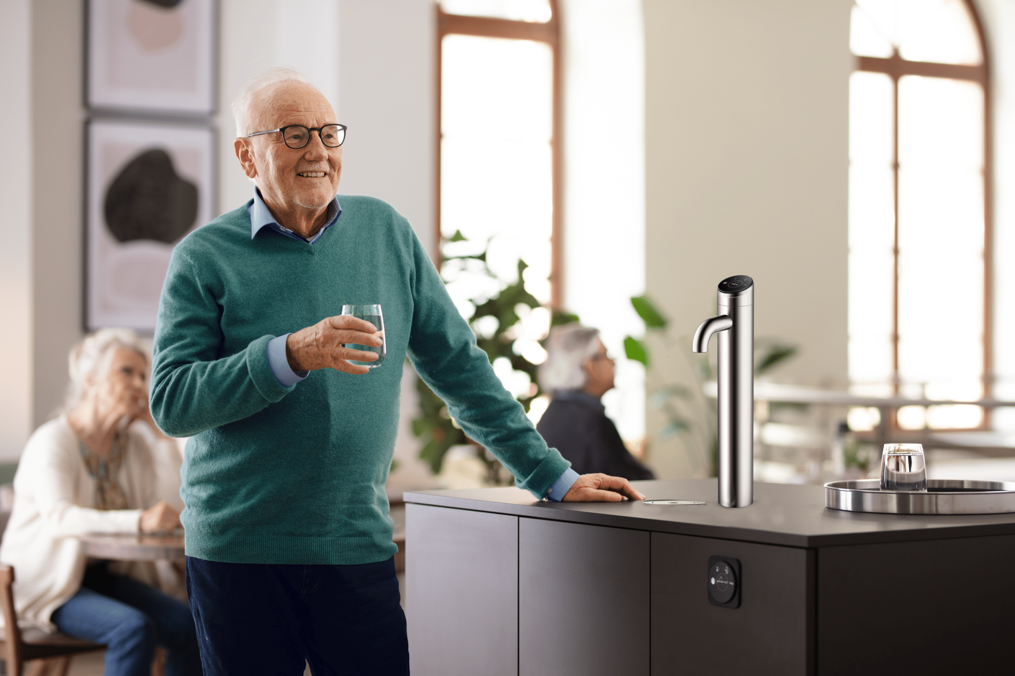 Senior man enjoying a glass of water near a modern hydration station in a community setting