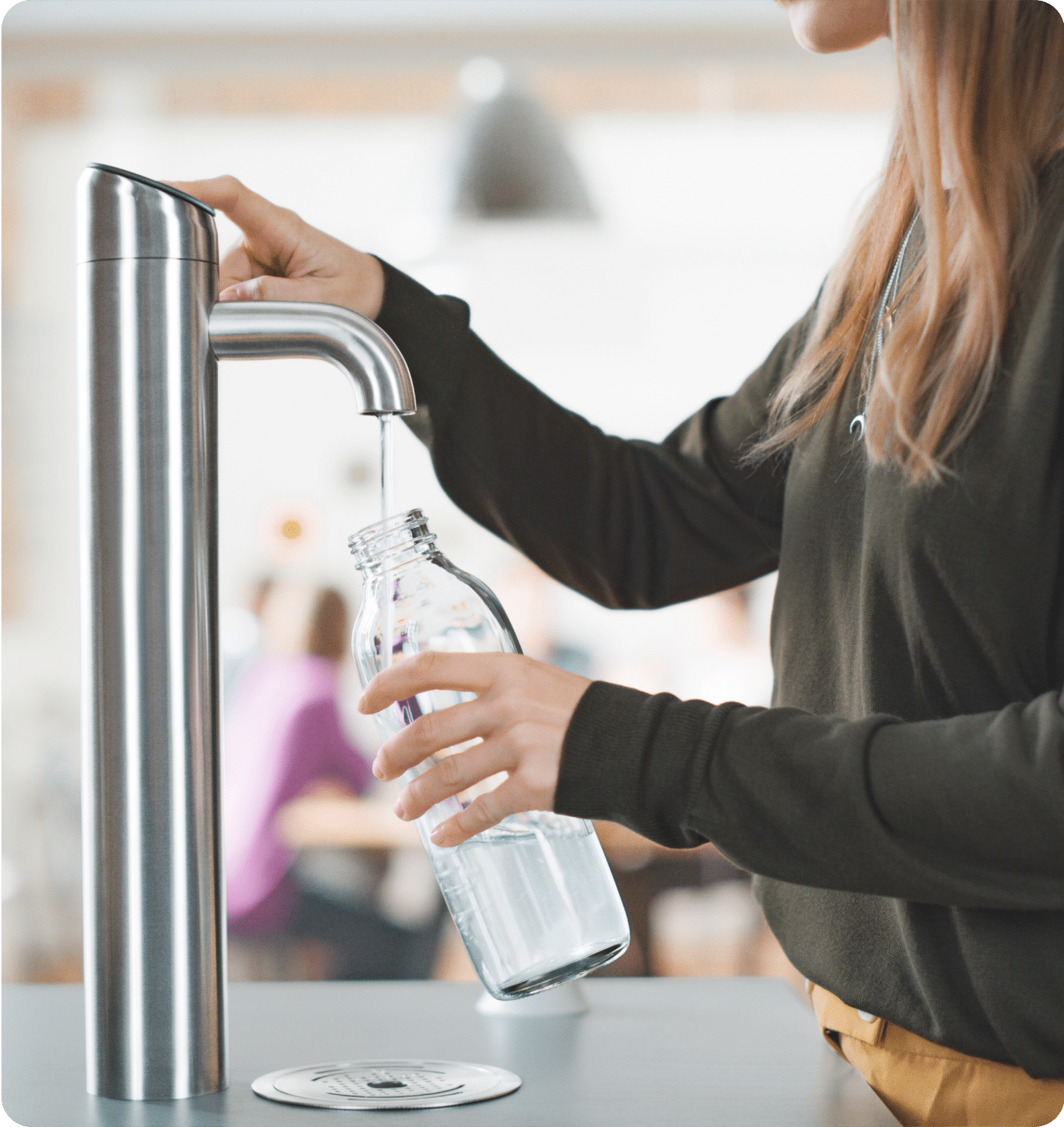 Person using water dispenser with glass