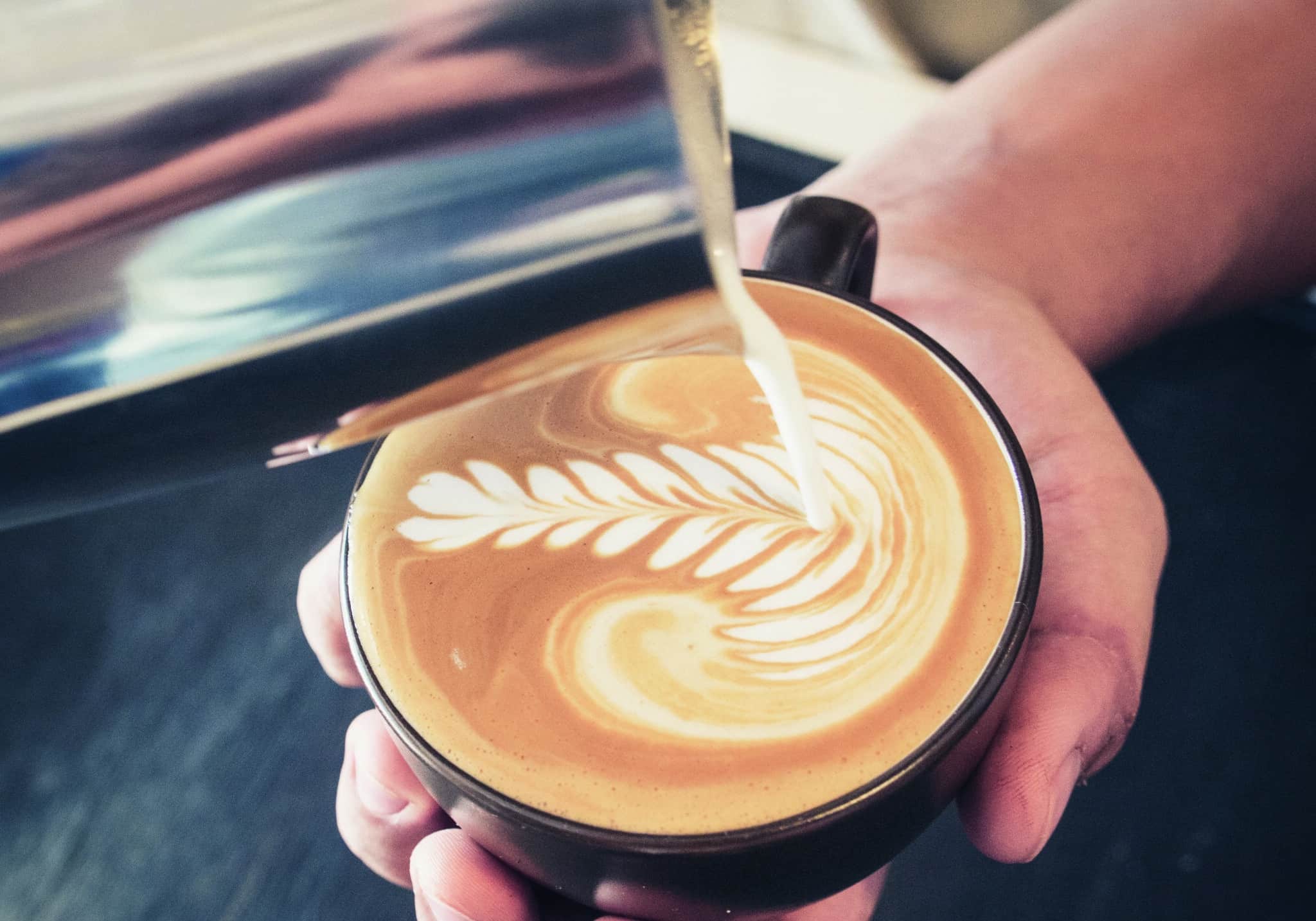 Close-up of latte art being created with milk being poured into a cup of coffee.