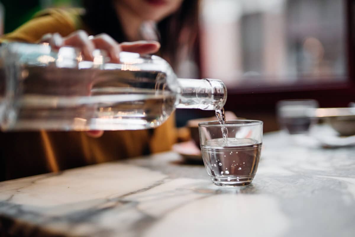 Close up shot of woman pouring water into glass