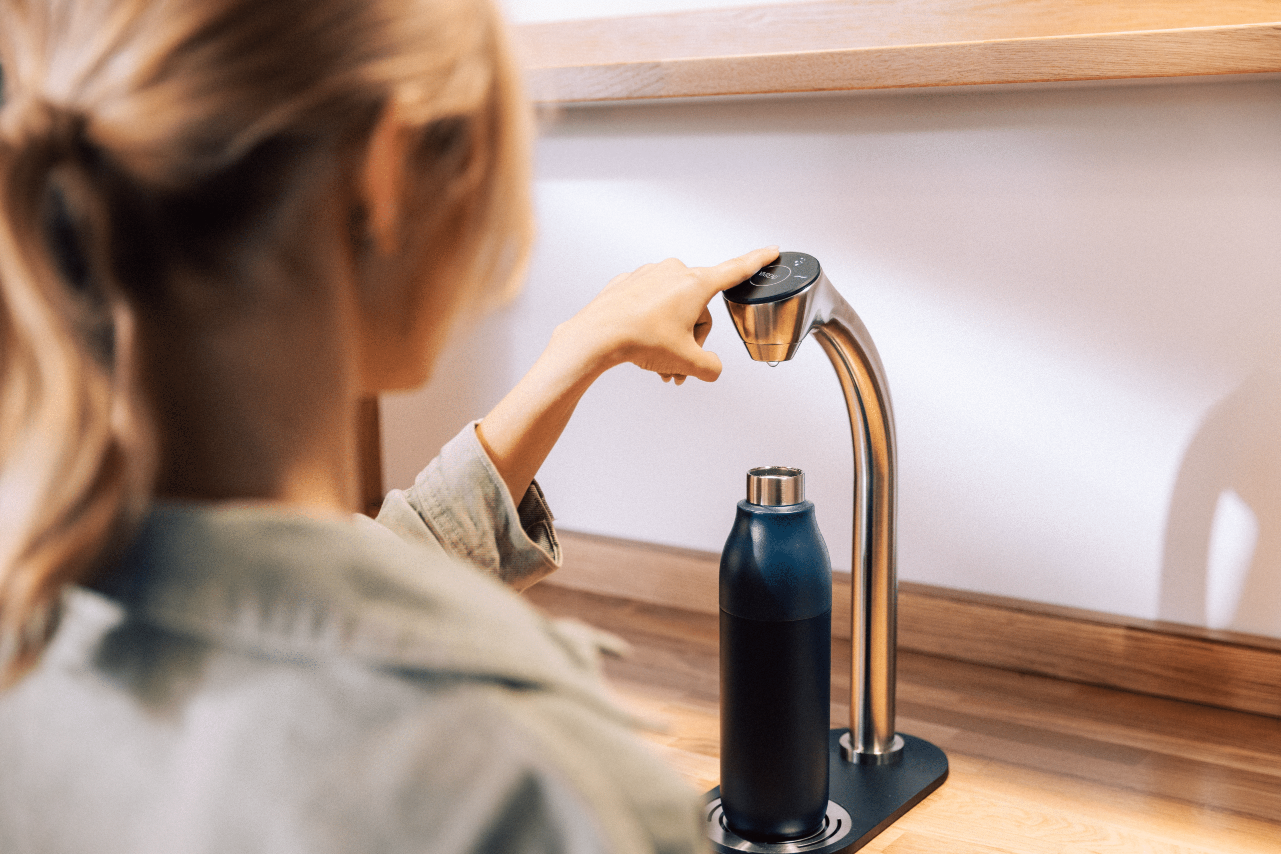 User refilling a reusable bottle with a Vivreau water dispenser