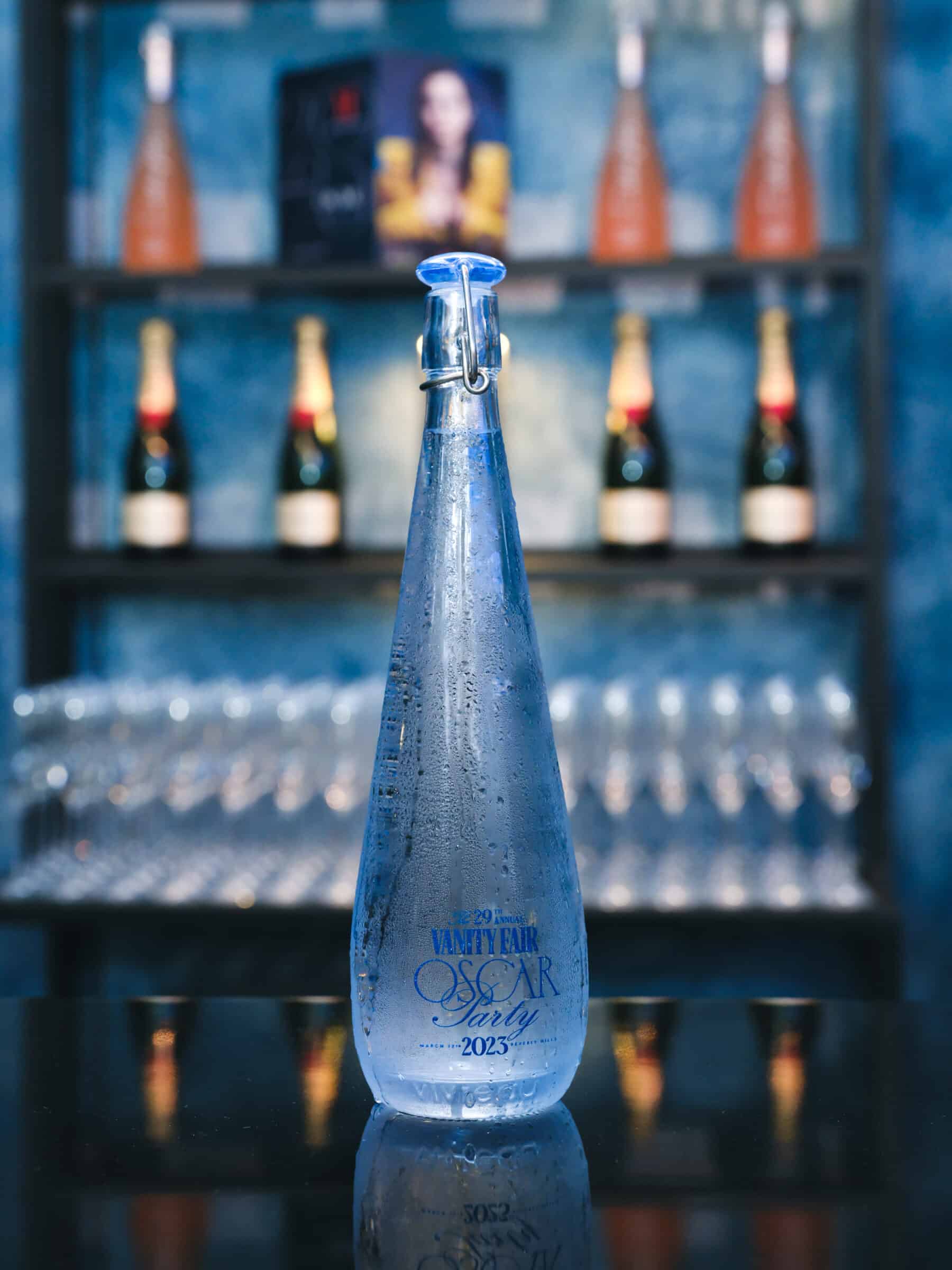 Elegant Vivreau glass bottle branded for the 2023 Oscar Vanity Fair Party, showcased with a background of champagne bottles and glasses