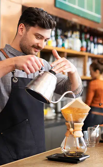 Barista brewing coffee using a Chemex pour-over coffee maker, focusing on the sensory experience of crafting coffee