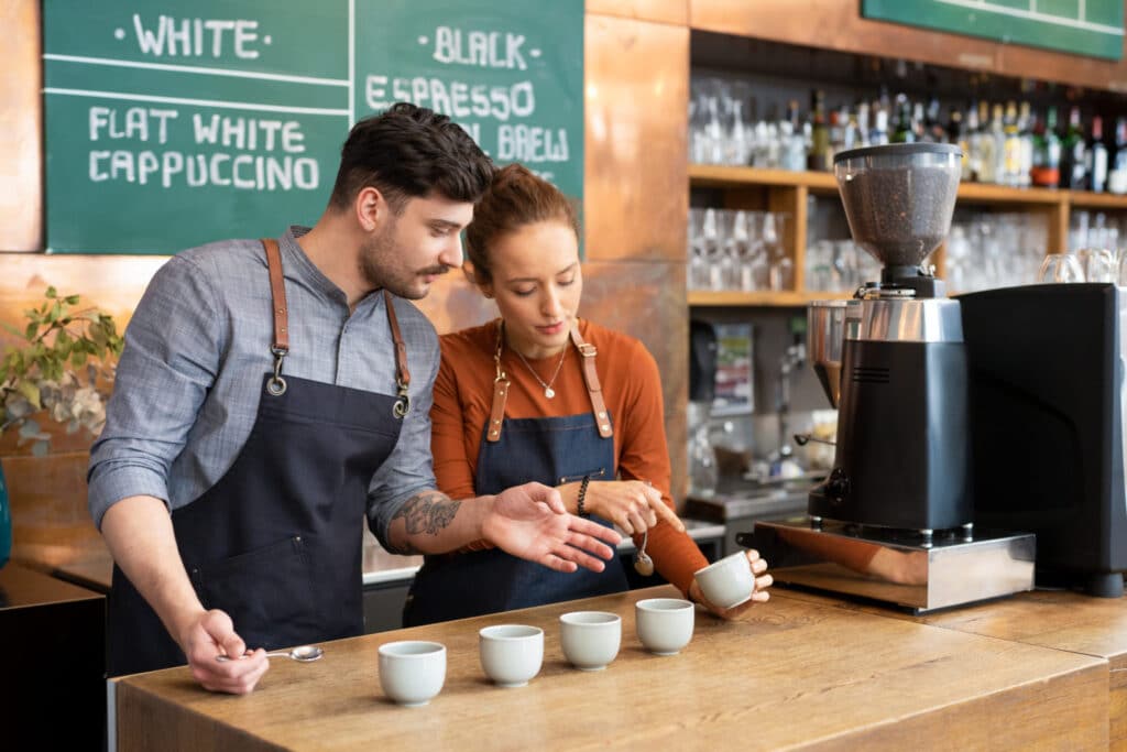 Baristas conducting a coffee tasting session with white cups on a wooden counter