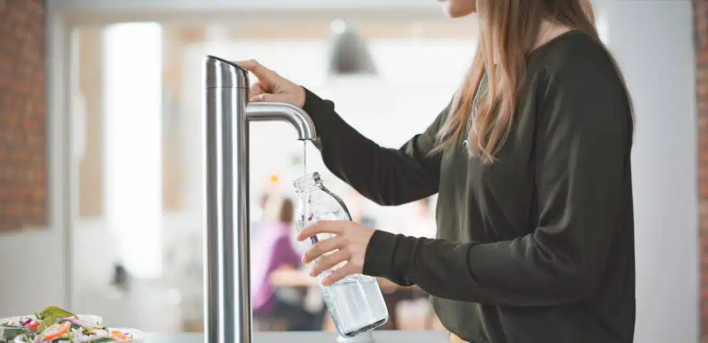 Woman filling a reusable water bottle from a Vivreau water dispenser