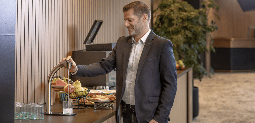 Man enjoying a refreshing glass of water at a hotel lobby self-serve hydration station