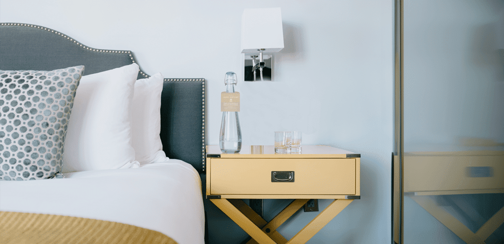 Elegant hotel room setup with a Vivreau water bottle on the nightstand