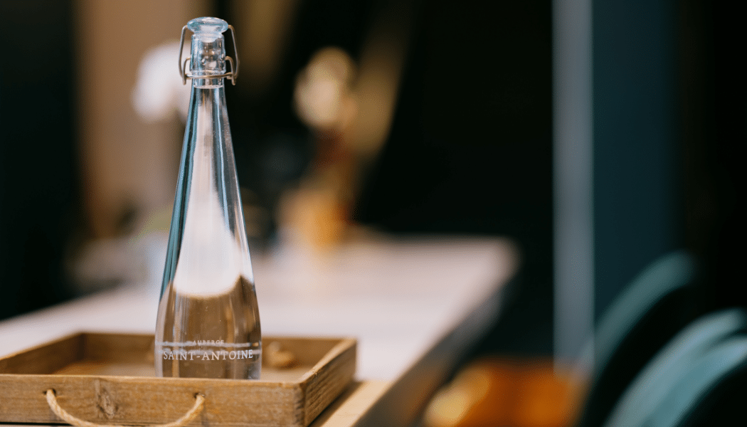 Reusable Vivreau glass water bottle placed on a wooden tray in a stylish dining setting