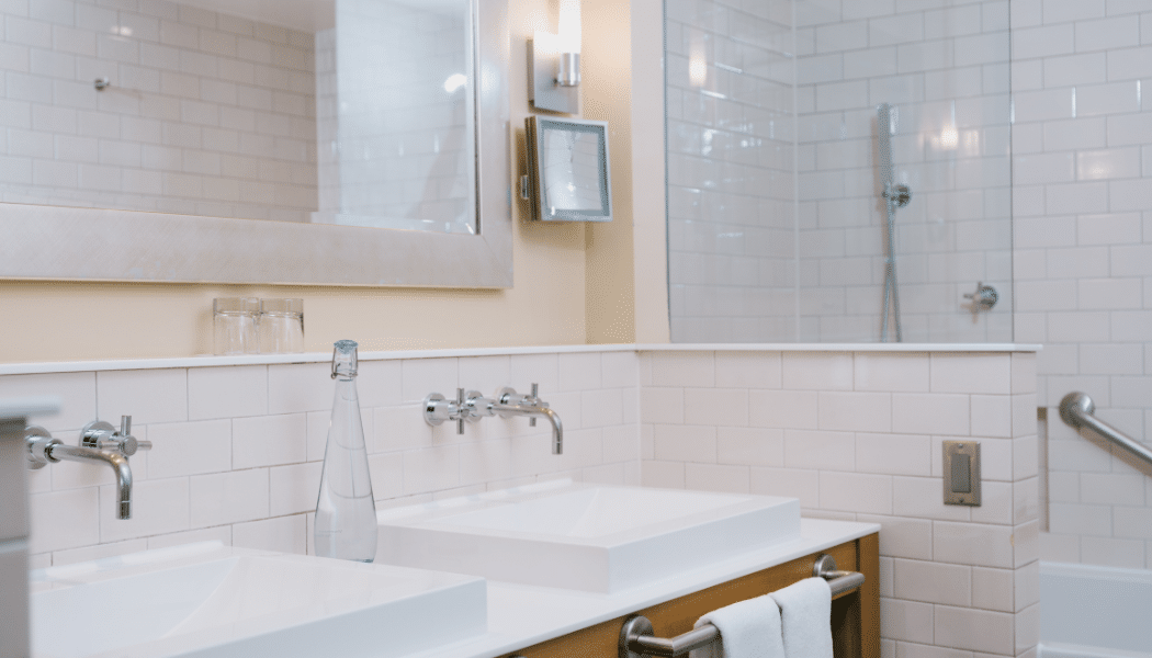 Elegant hotel bathroom with a Vivreau glass water bottle placed on a double-sink vanity