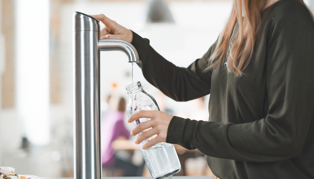 Filling a reusable glass bottle from a Vivreau water dispenser in an office environment