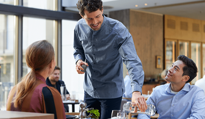 Pouring water out of custom glass bottles in restaurant